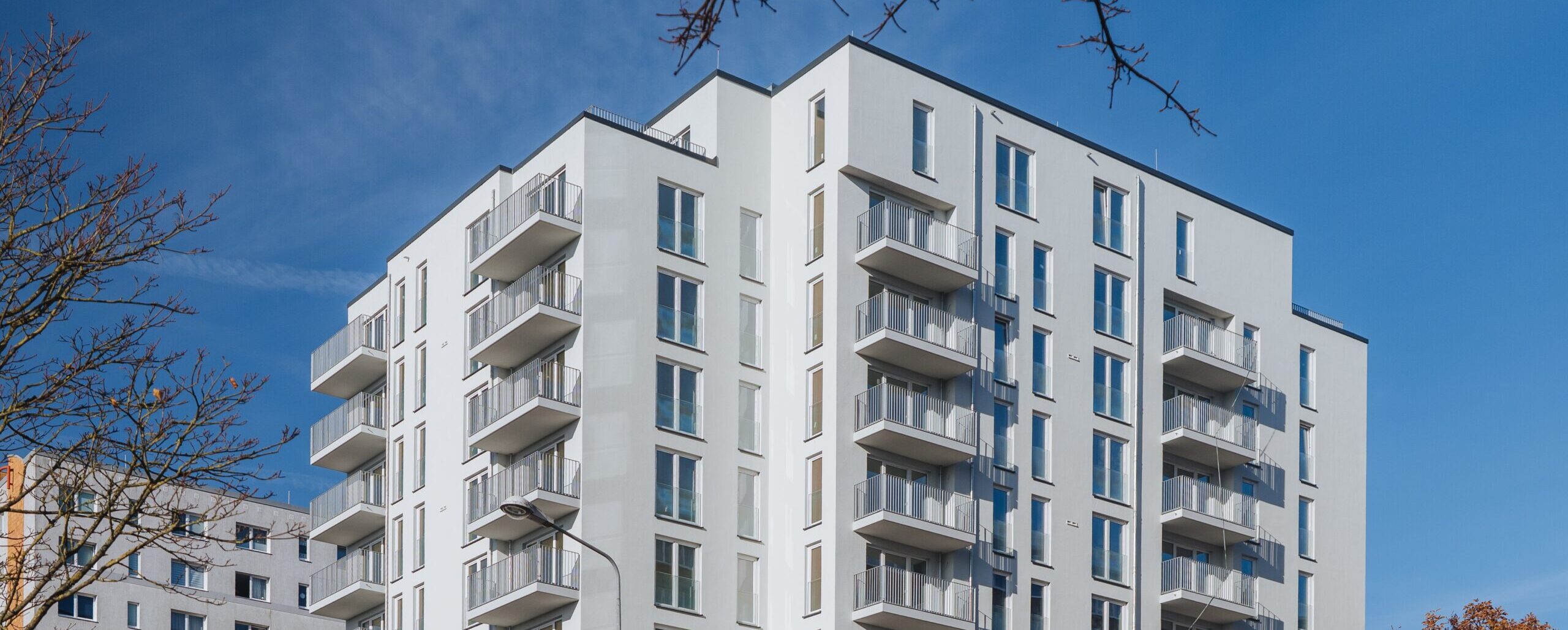 DSC_8577 Titel ein weißes Hochhaus vor blauem Himmel mit Balkonen und vielen bodentiefen Fenstern, Warnowallee 23a in Rostock Lütten Klein