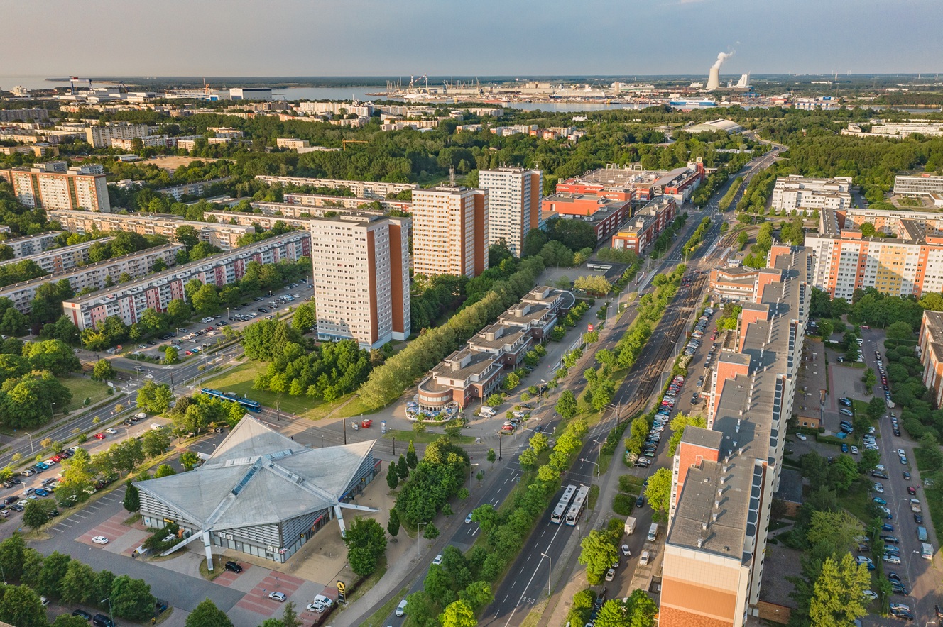 Luftaufnahme der Warnowallee in Lütten Klein mit Wohnhäusern, Grünflächen und Straßenbahntrasse.