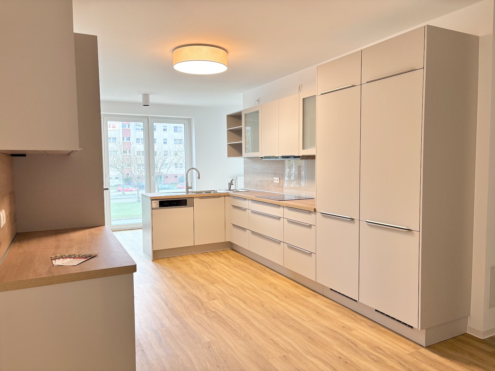 Moderne Gemeinschaftsküche mit viel Stauraum, Arbeitsflächen und bodentiefen Fenstern.