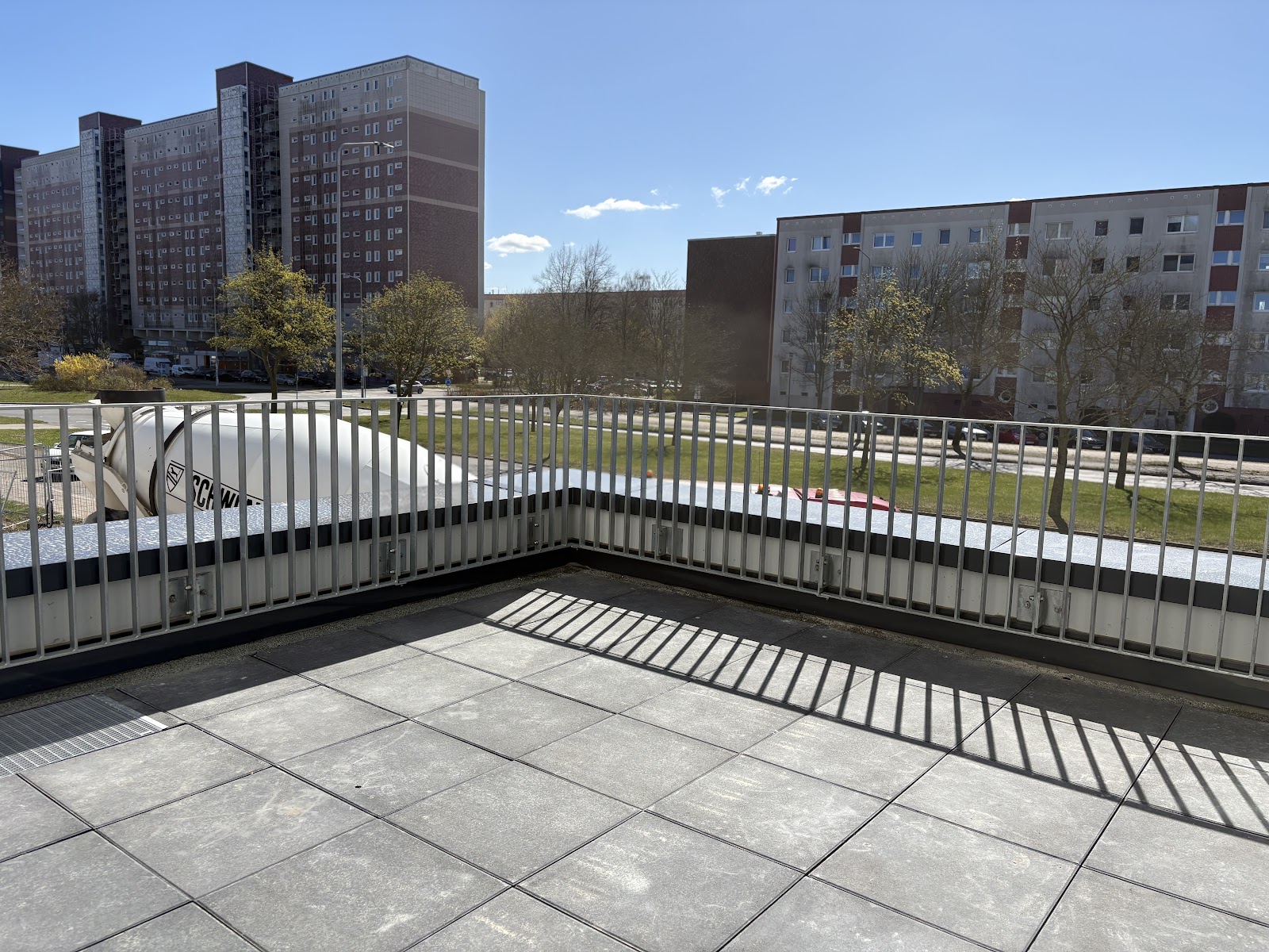 Befestigte Dachterrasse mit Geländer und Blick auf die Wohnhäuser der Umgebung.