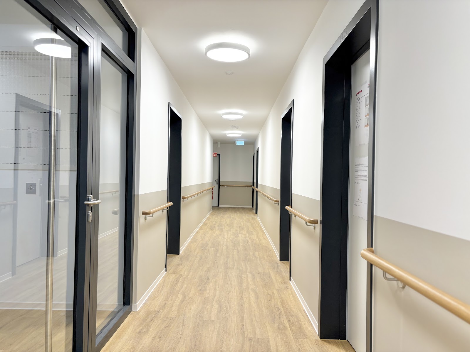 Heller Flur im Wohnhaus mit breiten Wegen, Handläufen und gut ausgeleuchteten Zugängen.